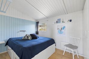 Ein Schlafzimmer mit Bett, einem Sessel, einem Fenster und Wanddekorationen.