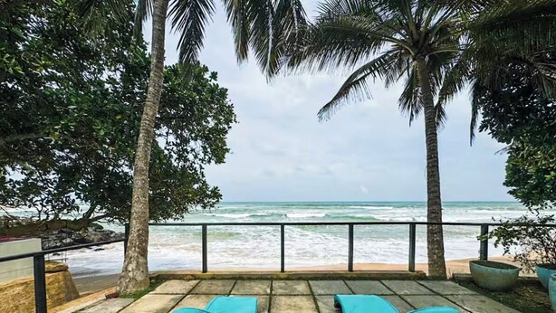 Une terrasse en bord de mer avec deux chaises longues et vue sur l’océan.
