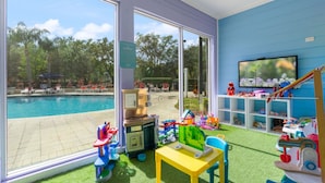 A room with a pool view, a play area with toys, and a TV on the wall. - Thematic 4 bdr House Near Disney - 11-105lv (Kissimmee)