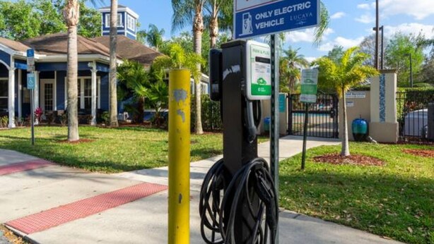 A no parking sign, electric vehicle charging station, and a building with a blue facade. - Thematic 4 bdr House Near Disney - 11-105lv (Kissimmee)