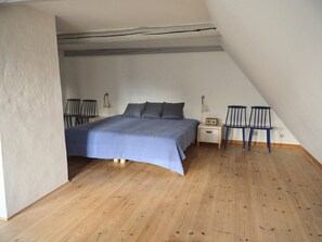 A bedroom with a bed, bedside table, lamp, and two chairs.
