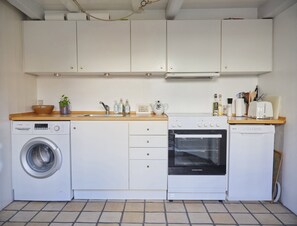 Una cocina funcional con lavadora, horno y una pequeña encimera con diversos objetos.