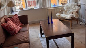 A cozy living room with a brown leather sofa, a wooden coffee table, and a white furry chair.