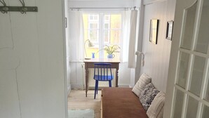 A narrow room with a bed, a desk, and a window.