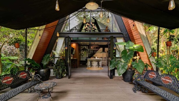A cozy, modern interior with a wooden floor, a central seating area with a table, and potted plants. - Intragama Villa (Cisarua)