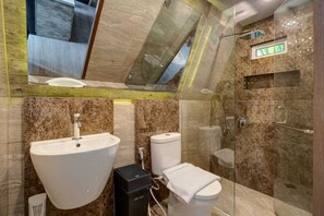 Un baño moderno con ducha de vidrio, lavamanos blanco y retrete.
