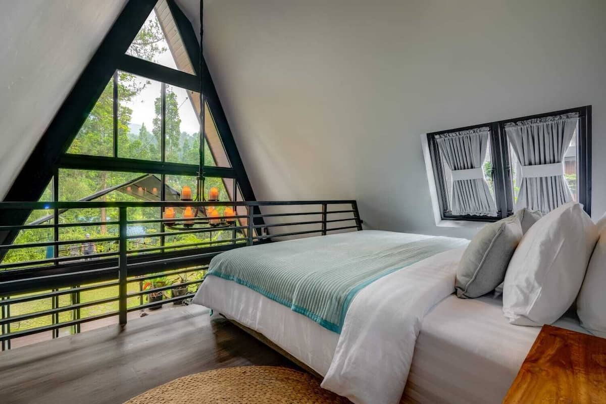 Une chambre avec une grande fenêtre, un lit et une vue sur la verdure.