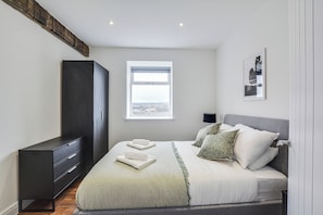 Un dormitorio con cama, armario, ventana y un cuadro en la pared.