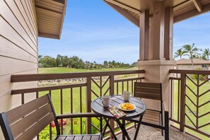 Un balcon avec une table, des chaises et une assiette de fruits.