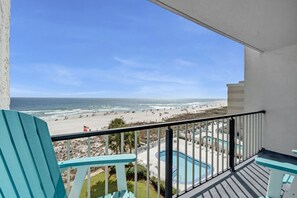 A balcony with a view of a beach and a swimming pool. - You are practically on the beach, it is that close! (Orange Beach)