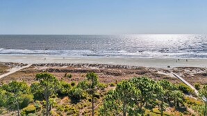 En strand med kig til havet, en sandsti og sparsom beplantning.