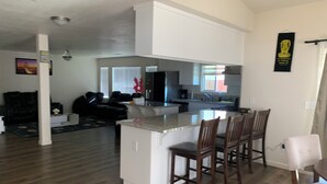 A modern kitchen with a central island and bar stools, a dining area with a table and chairs, and a living room with a sofa and a coffee table. - Spacious 5BR/3BA Family Home in Riverbank (Riverbank)