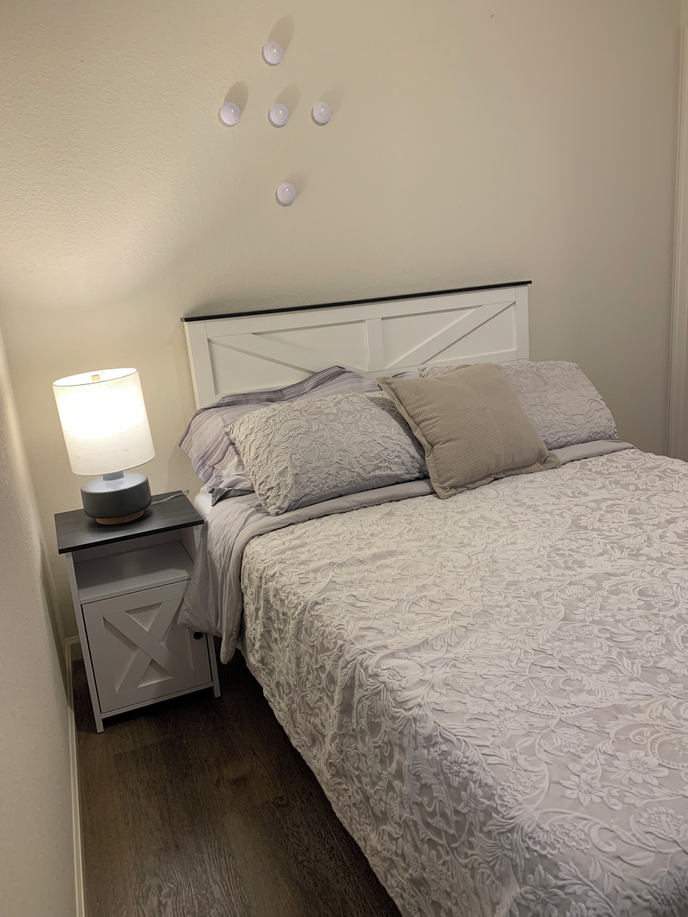 A neatly made bed with a patterned bedspread, a bedside lamp, and a nightstand with a drawer.