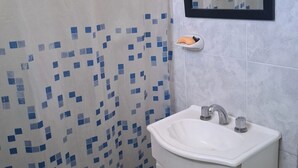 Kylpyhuone, jossa on suihkuverho, pesuallas, peili ja wc.