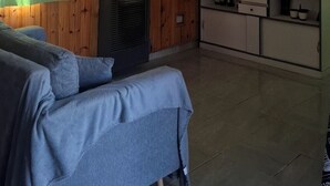 Olohuoneessa on sohva, televisio sekä keittiöalue, jossa on kaappeja ja mikroaaltouuni.
