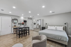 A modern hotel room with a large bed, a dining area with a table and chairs, and a kitchen area. - Fabulous 5 Bedroom Elegance Near LSU -Single Level home with Mother-in-Law suite (Baton Rouge)