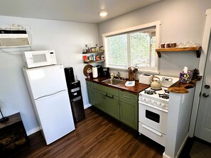 A kitchen with a refrigerator, microwave, coffee maker, stove, and wooden cabinets.