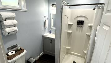 A bathroom with a toilet, sink, mirror, and shower.