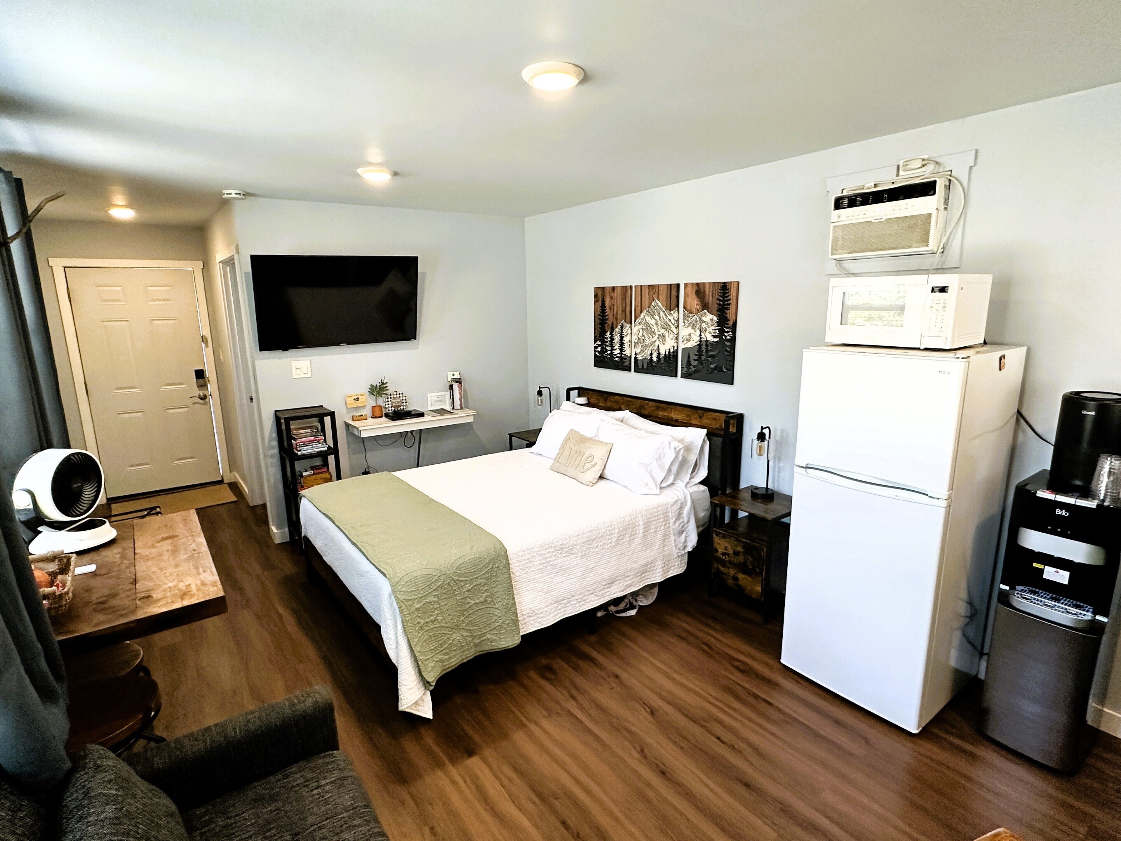 A hotel room with a bed, a TV, a microwave, a refrigerator, and a coffee machine.