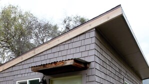 Ein eingeschossiges Gebäude mit einer grünen Tür, einem kleinen Fenster und einem sichtbaren Wasserhahn.