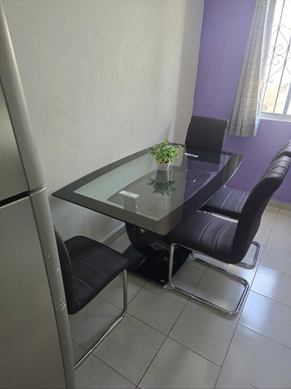 A conference table with four chairs, a small potted plant, and a window with curtains.