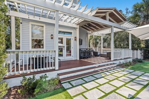 Une terrasse couverte avec une plateforme en bois, des rampes blanches et une structure en forme de pergola.