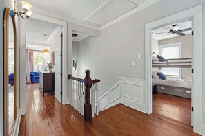 Une pièce spacieuse avec un plancher en bois, un lit superposé, un ventilateur de plafond et une vue sur un balcon.