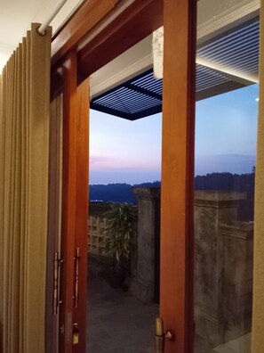 A wooden door leading to a balcony with a view of the sky and distant landscape. - Awan Cita Villa Munduk (Seririt)