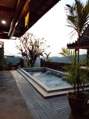 Un bain Ă remous sur une terrasse en bois, avec vue sur une chaĂźne de montagnes.