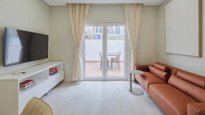 Una sala de estar moderna con un televisor de pantalla plana, un sofá, una mesita y una estantería.