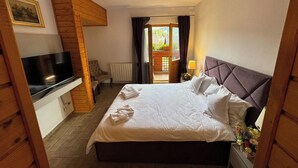A hotel room with a large bed, a TV on a wooden cabinet, a chair, and a view of the outdoors through a door. - Villa Alisio w. Sauna, Jacuzzi, Gym, BBQ (Sinaia)