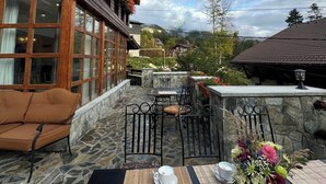 A wooden building with large windows and a balcony with stone flooring and metal furniture. - Villa Alisio w. Sauna, Jacuzzi, Gym, BBQ (Sinaia)