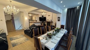A modern living room with a dining area, a staircase, and a kitchen in the background. - Villa Alisio w. Sauna, Jacuzzi, Gym, BBQ (Sinaia)