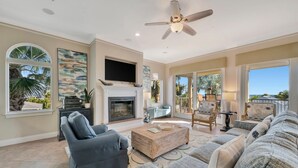 A spacious living room with a fireplace, comfortable seating, a flat-screen TV, and large windows. - Large Beachfront 3B Condo | Heated Pool & Hot Tub (Holmes Beach)