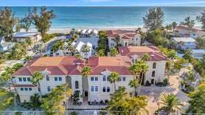 A coastal residential area with multiple houses, a beach, and palm trees. - Large Beachfront 3B Condo | Heated Pool & Hot Tub (Holmes Beach)