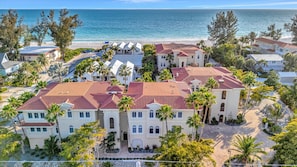 A coastal residential area with multiple houses, a beach, and palm trees.