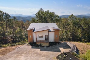 A small house with a sloped roof, a front porch, and a stone pathway leading to the entrance. - Modern home with Mountain Views, Hot Tub, EV outlet, Family and Dog friendly, (Mineral Bluff)