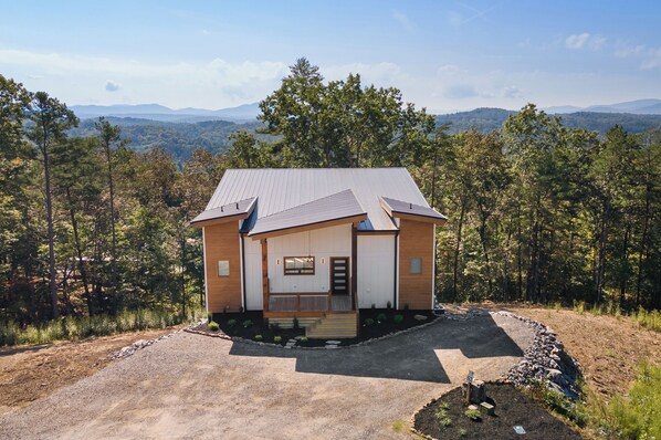 Una casa petita amb un teulat inclinat, un porxo davanter i un camí de pedra que porta a l'entrada.