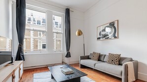 Uma sala de estar moderna com um sofá, uma mesa de centro e um quadro na parede.