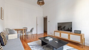 Uma sala de estar moderna com sofá, mesa de centro, televisão e um pequeno armário.