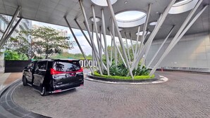 A modern building with a circular skylight design and a black SUV parked in front. - Summit By SanLiving - 2BR (Jakarta)
