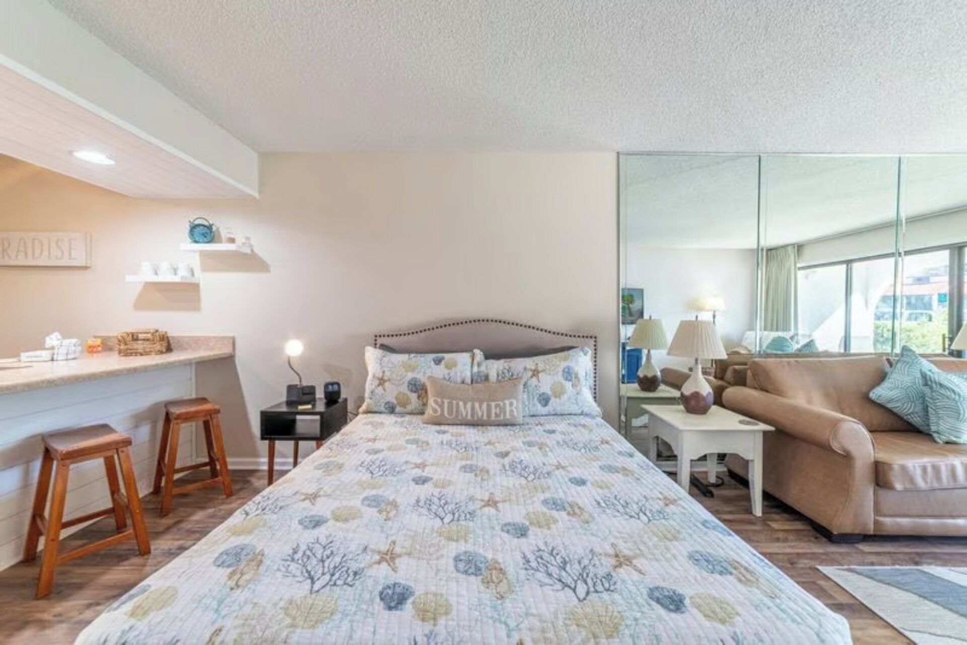 A bedroom with a bed, a nightstand, a desk, a chair, and a sofa.