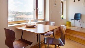 Un espace repas comprenant une table et des chaises, de grandes fenêtres et une vue sur la ville.