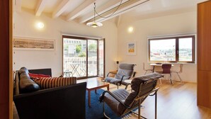 Un vaste espace de vie comprenant un canapé, des fauteuils, une table à manger et un balcon avec vue.
