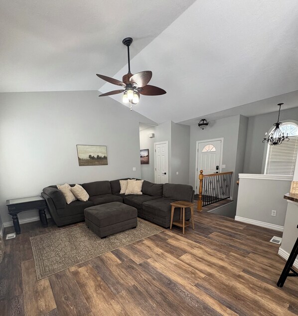 A living room with a sectional sofa, a small wooden table, a rug, and a ceiling fan.