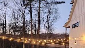 An outdoor patio with stone flooring, a seating area with chairs, and string lights. - Peaceful New Home Close to Helen/Hot Tub/Theater/Game Room/Firepit (Cleveland)