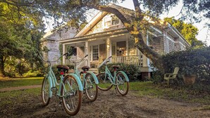 A house with a porch, two bicycles, and a chair.