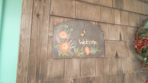 A welcome sign with floral and butterfly designs on a wooden wall.
