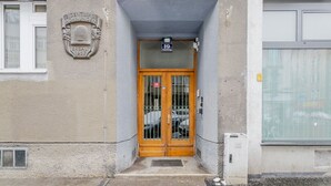 A building entrance with a wooden door, a plaque above it, and a sign above the door. - Blueground | Wieden, washer/dryer, nr Karlskirche (Vienna)