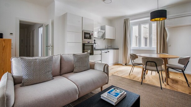 A compact living space with a sofa, dining table, and kitchenette. - Blueground | Wieden, washer/dryer, nr Karlskirche (Vienna)